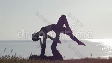 在露天冥想，女人和<strong>男</strong>人在海上和日落的背景下在山上做<strong>双人</strong>瑜伽